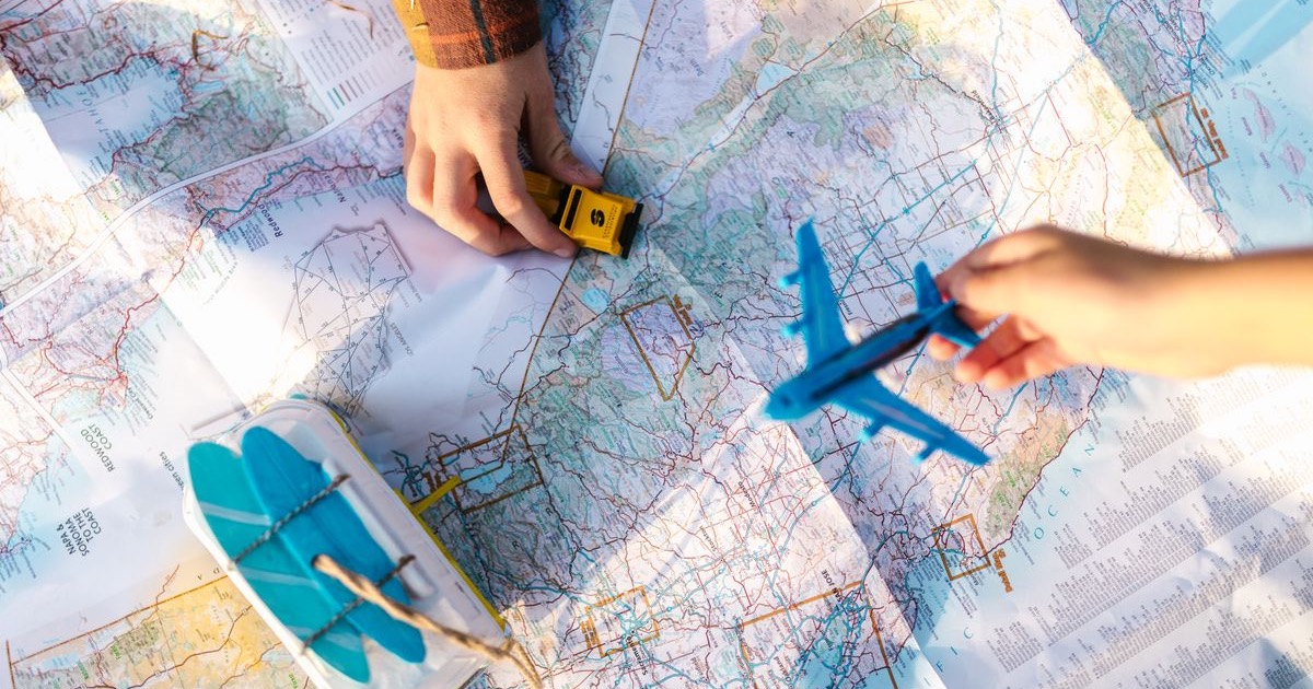 Des enfants comparent une petite voiture et un avion au-dessus d’une carte pour préparer un voyage vers Orlando.